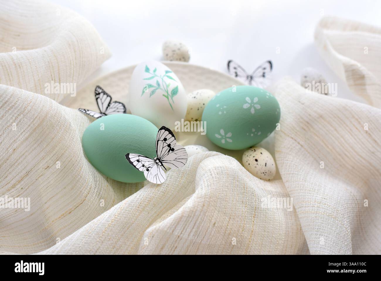 Eleganti uova di pasqua e farfalle su un panno di lino su un piatto bianco. Concetto di buona Pasqua Foto Stock