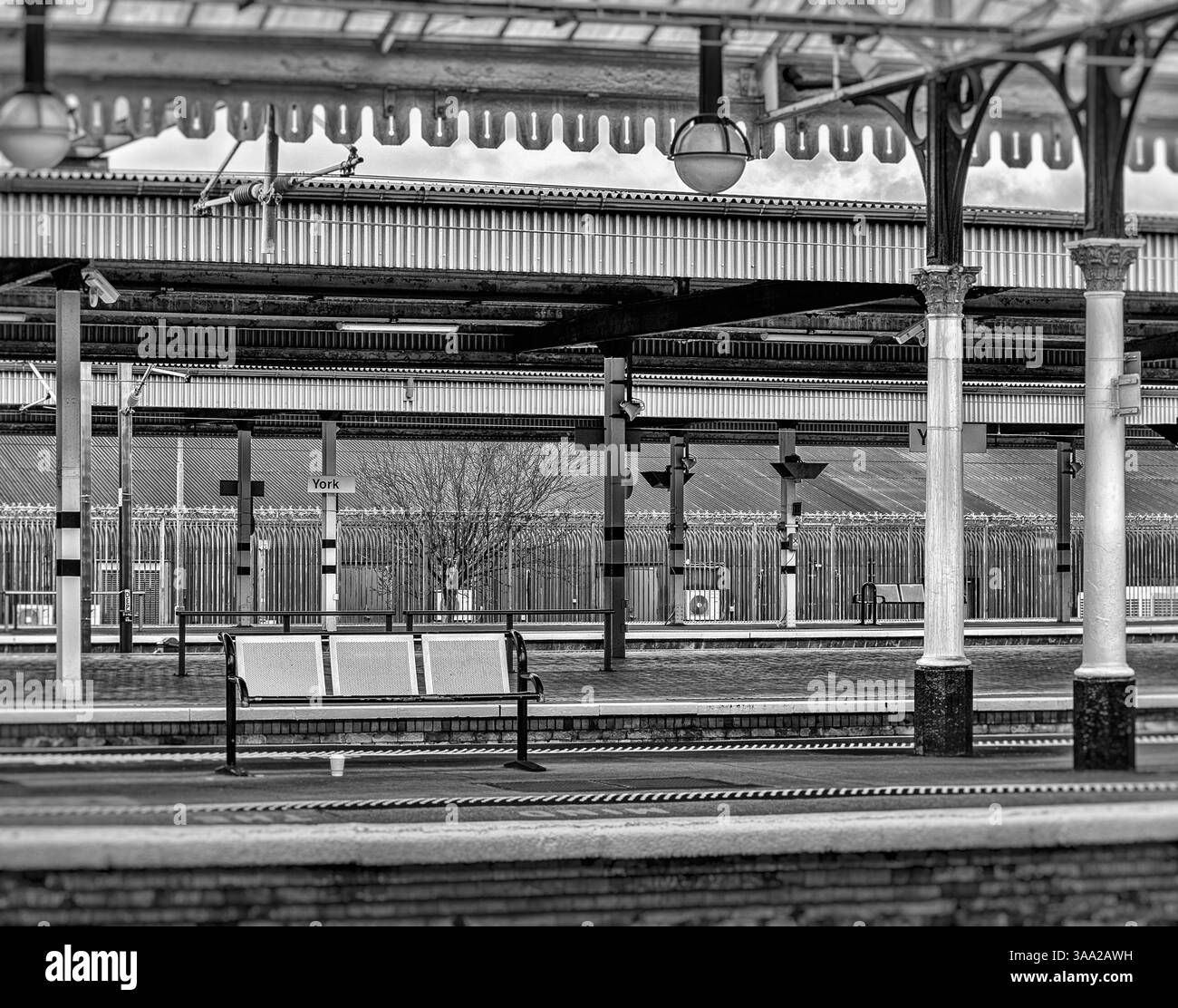 Una storica piattaforma della stazione ferroviaria del XIX secolo con colonne architettoniche. Una tazza di caffè scartata è stata lasciata sotto un banco di metallo. Foto Stock