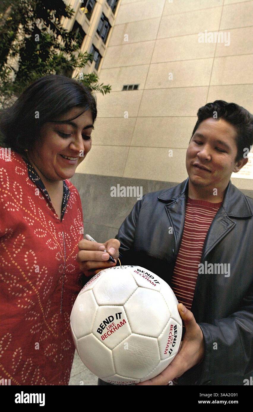Gurinder Chadha guarda suo marito e scrittore Paul Mayeda Berges firmare un pallone da calcio promuovendo il film a cui hanno lavorato insieme. Lui è lo scrittore e lei è la regista di ''Bend IT Like Beckham'', un film sul futbol. Foto scattata a San Francisco, venerdì 7 marzo 2003. Manny Crisostomo/Sacramento Bee/ZUMA Press Foto Stock