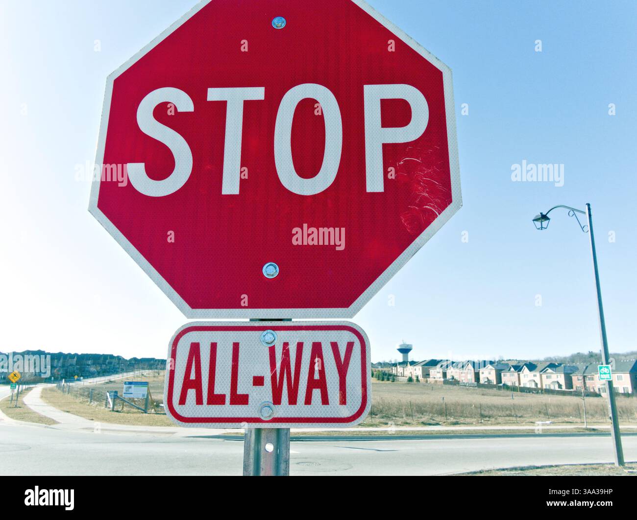 In un tranquillo ambiente periferico, un segnale di stop riflettente ricorda ai passanti la prudenza e la responsabilità della comunità Foto Stock