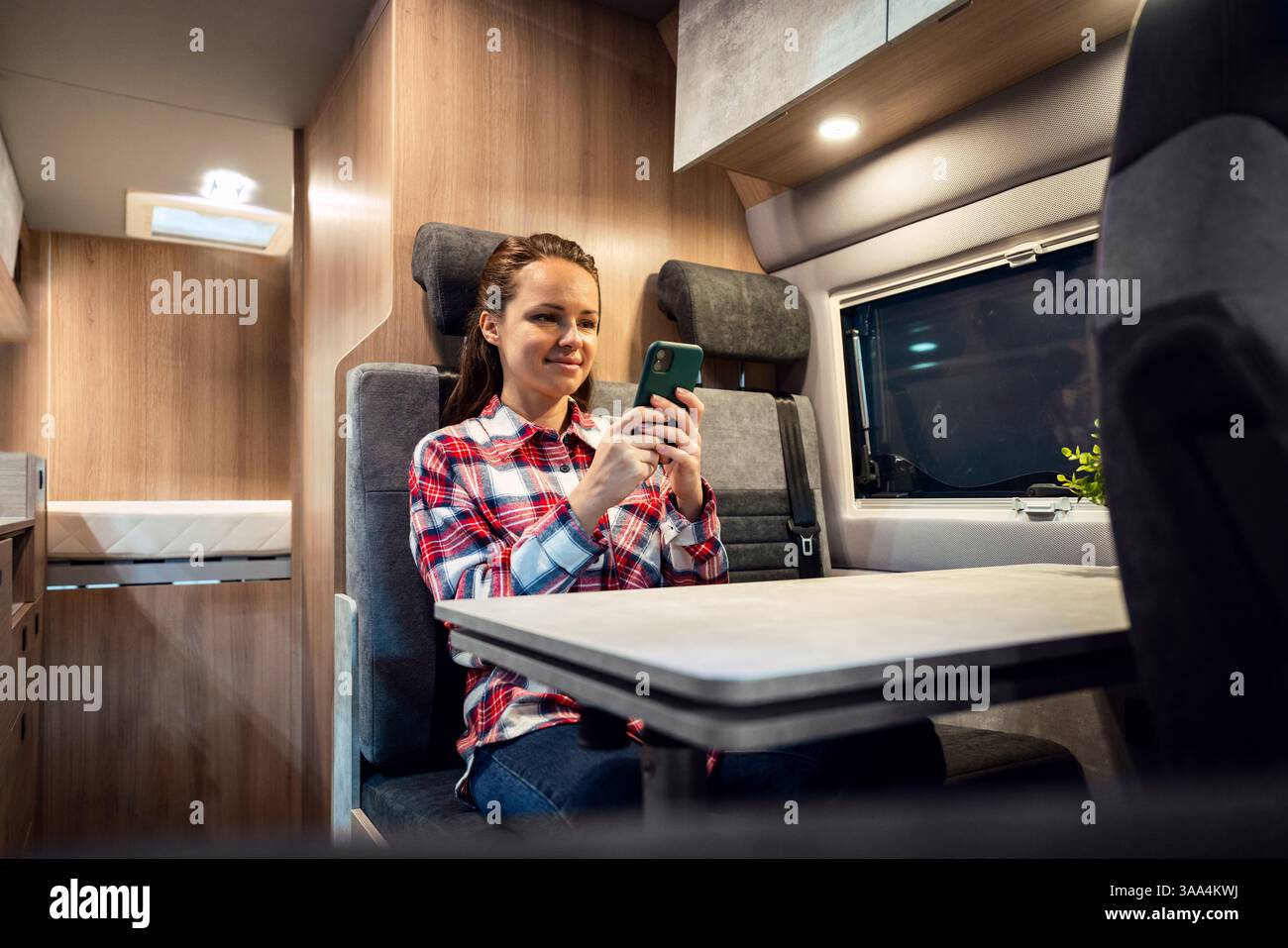 Donna camper che usa il telefono cellulare al tavolo all'interno del camper Foto Stock