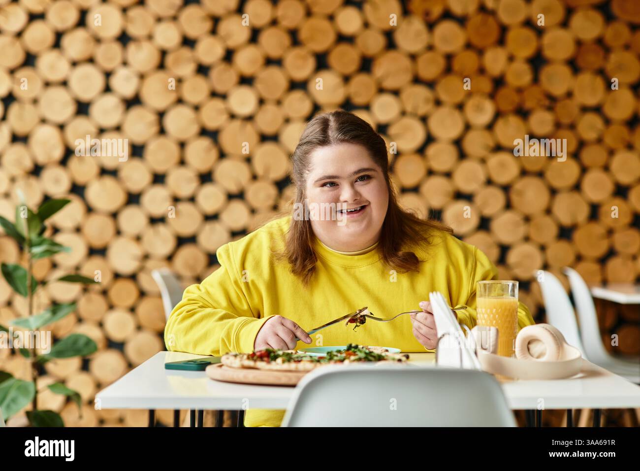 Una donna sicura di sé con la sindrome di Down gode di un pasto gioioso in un bar. Foto Stock