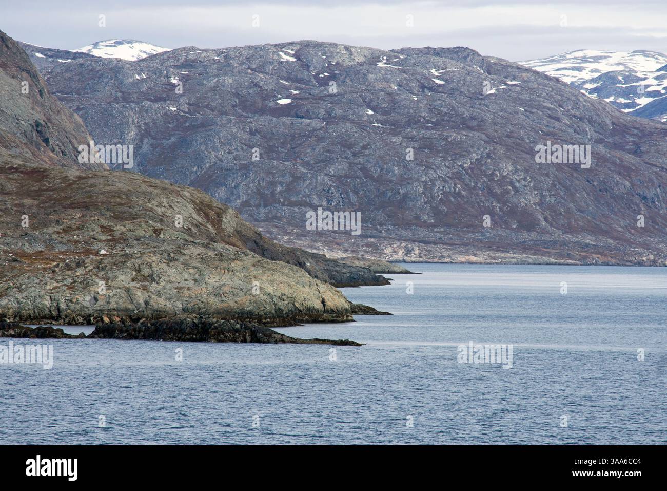 Vista mozzafiato delle torreggianti montagne che circondano le tranquille acque del fiordo di Arsuk, Groenlandia, mostrando la splendida bellezza del paesaggio artico Foto Stock