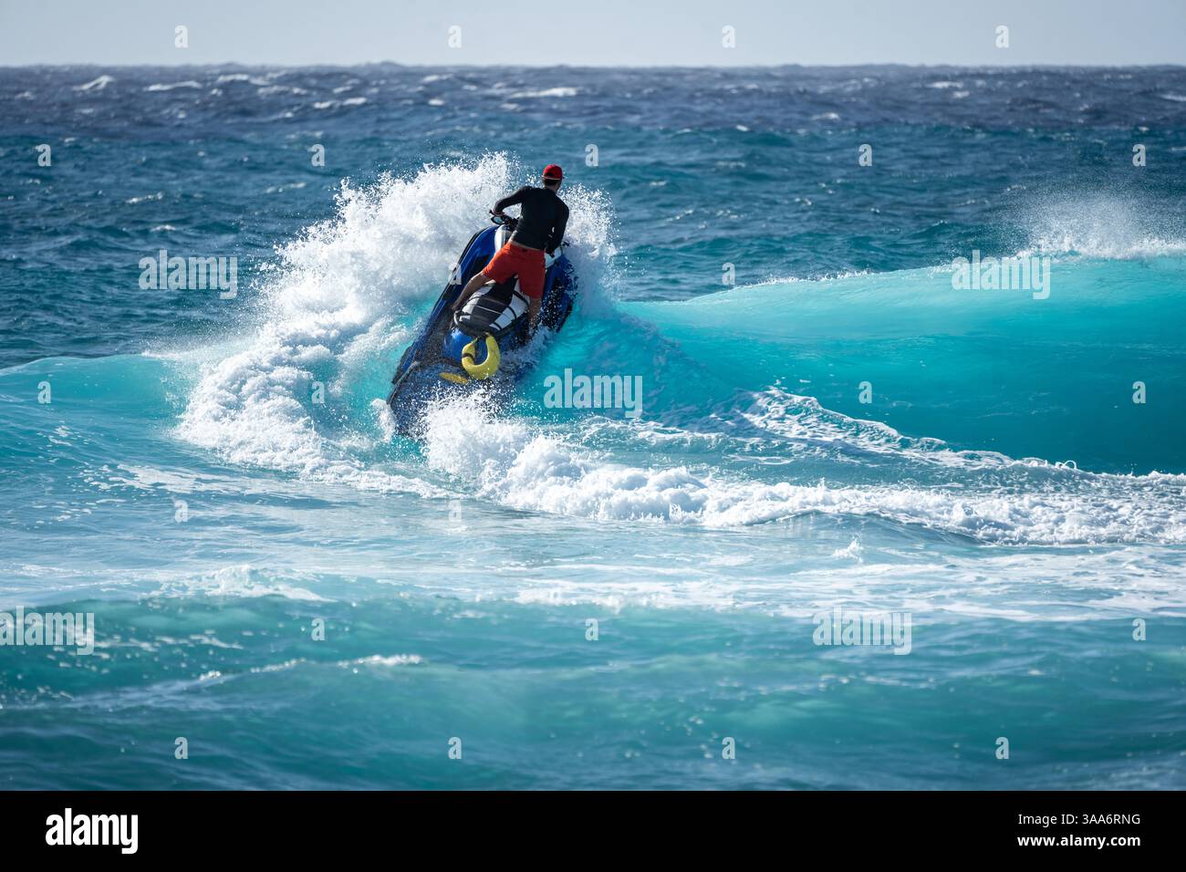 Man on Search and Rescue Ocean Ski che si schianta attraverso Blue Ocean Wave Outbound to Sea - tema operativo di risposta bagnino Foto Stock