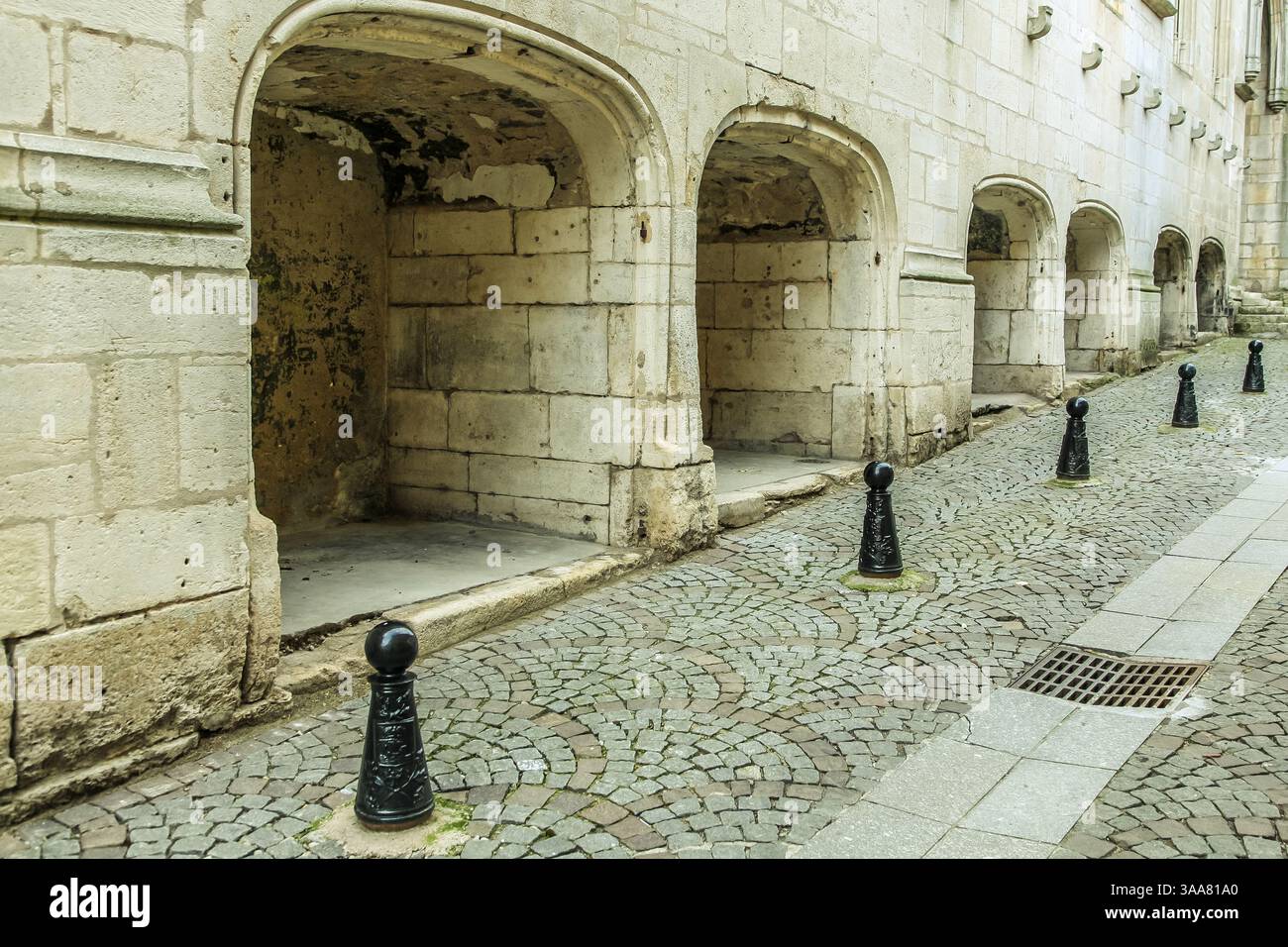 Una fila di pali di metallo nero sono allineati su una strada acciottolata. I montanti sono distanziati uniformemente e disposti in fila Foto Stock