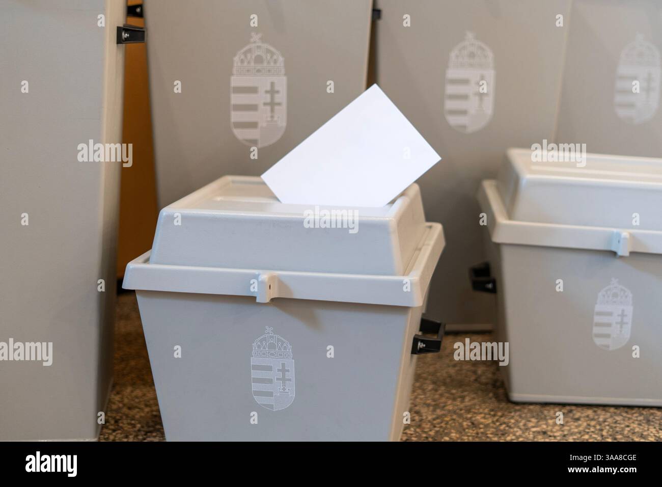 Urna con stemma ungherese e busta di voto su un tavolo Foto Stock