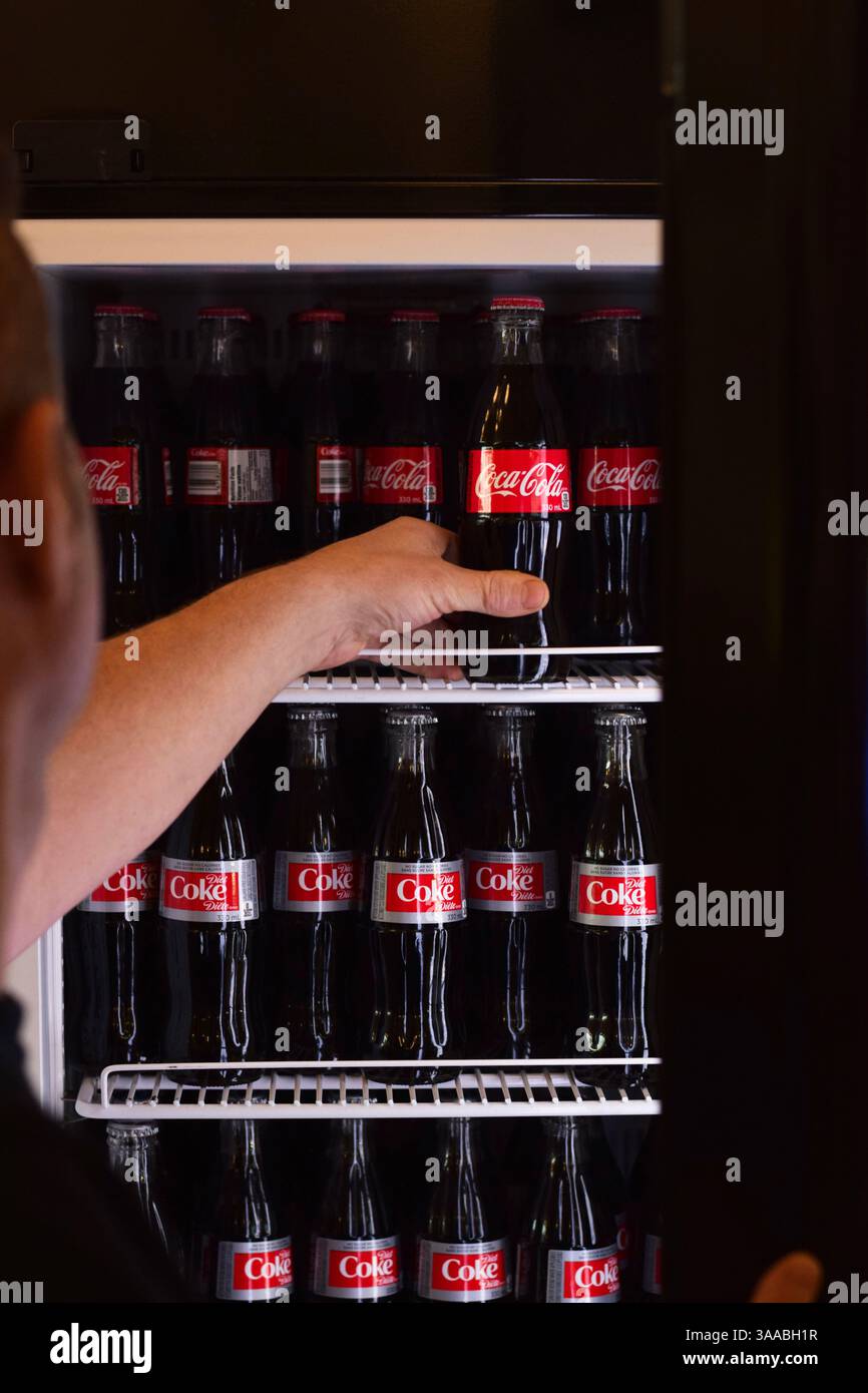 19 ottobre 2020 a Thornhill, Ontario Canada: Mano dell'uomo che entra in frigorifero in un negozio per prendere una bottiglia di Coca Cola Foto Stock