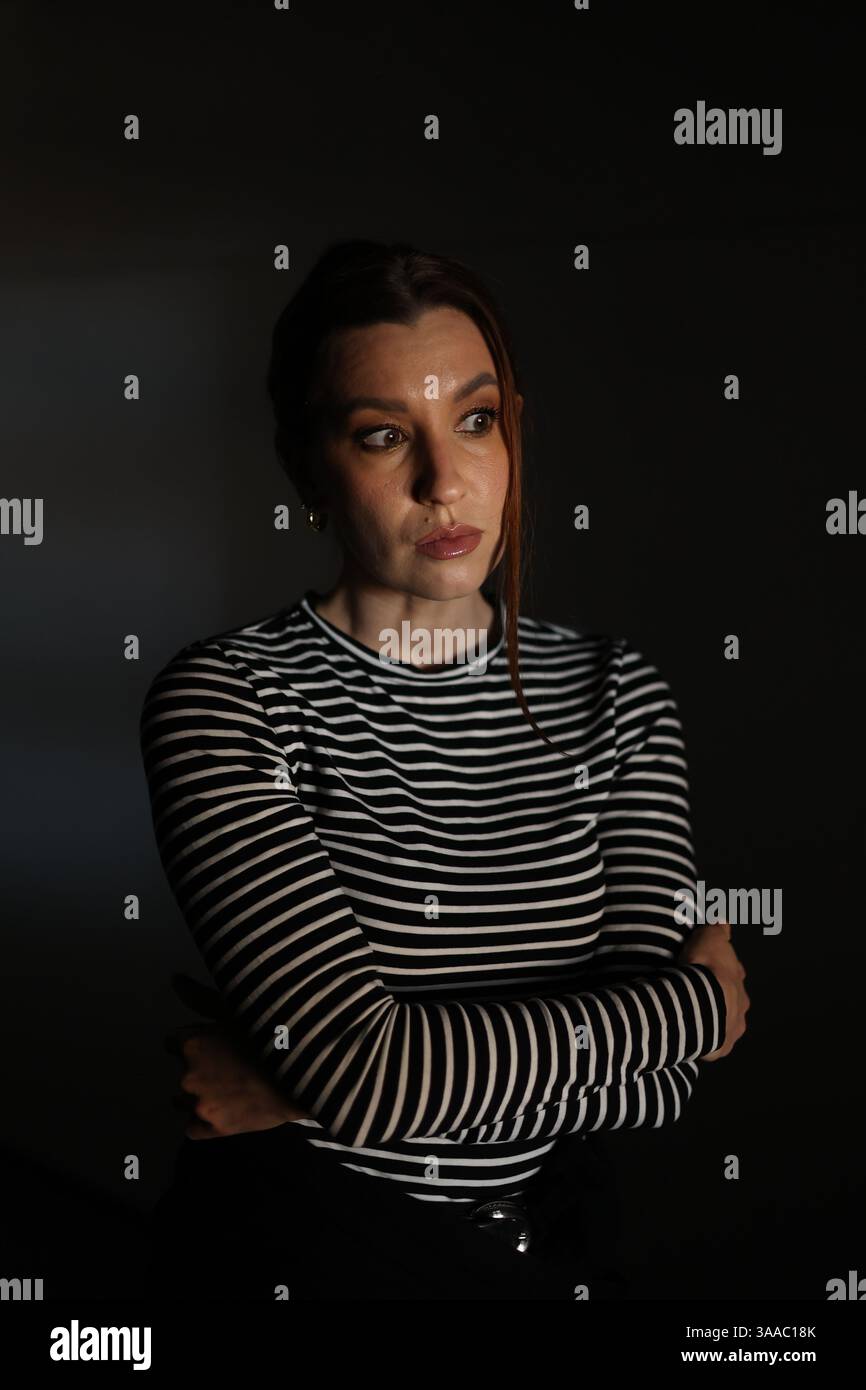 ritratto drammatico di una bella ragazza che guarda attentamente di lato. eccitazione, indifferenza, risentimento, ostilità. al crepuscolo al buio Foto Stock
