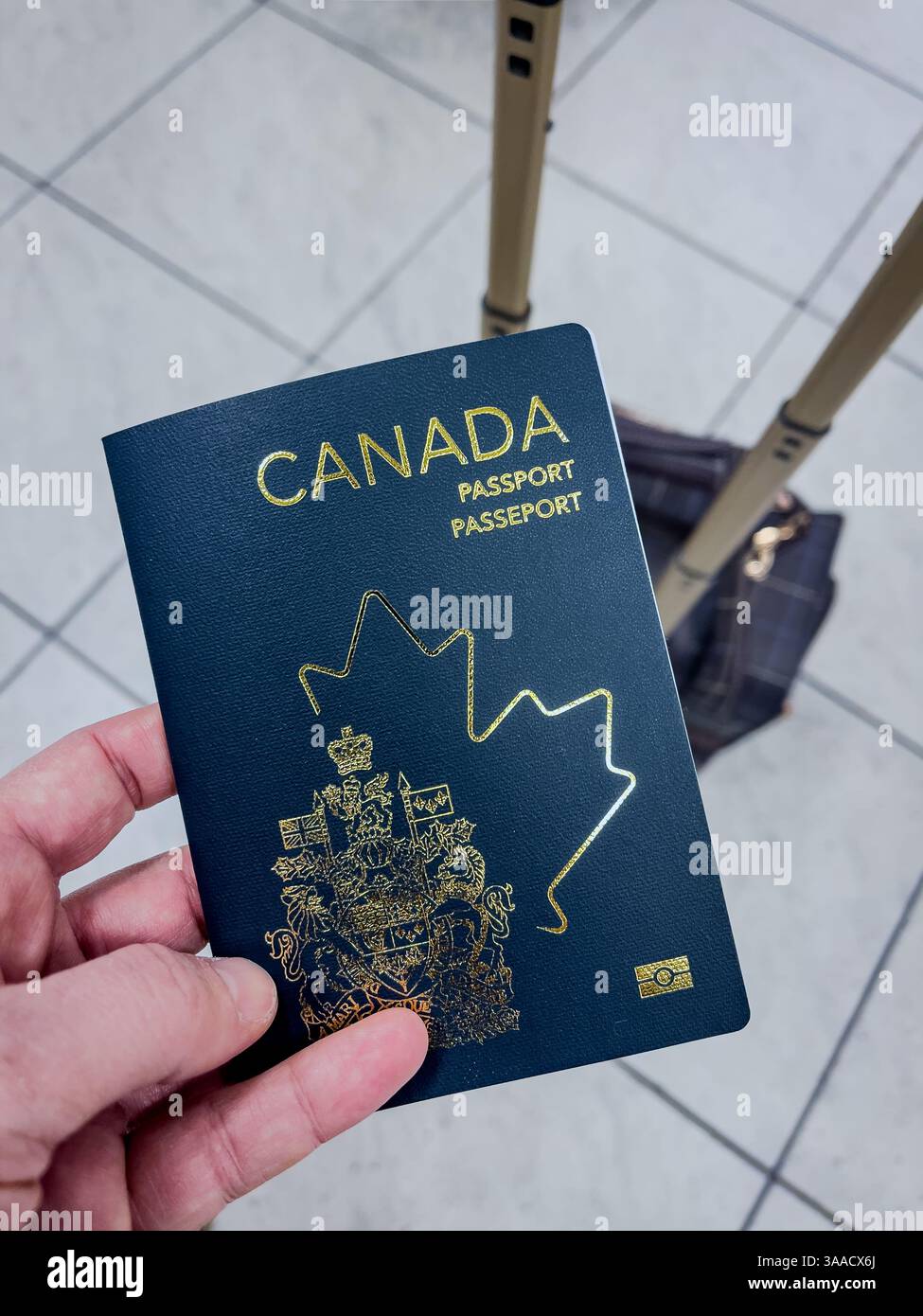 Un passaporto canadese tenuto da una persona, con una valigia sullo sfondo in un aeroporto. Perfetto per viaggi, immigrazione e temi di identità. Foto Stock