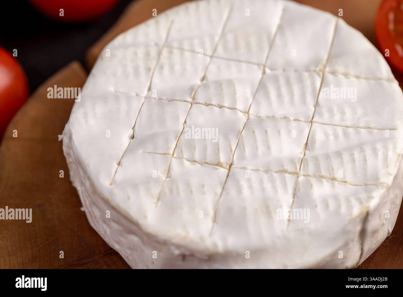 formaggio morbido con muffa e pomodori rossi maturi, un pezzo di formaggio morbido maturo e alcuni piccoli pomodori rossi rotondi sul tavolo, vista dall'alto Foto Stock