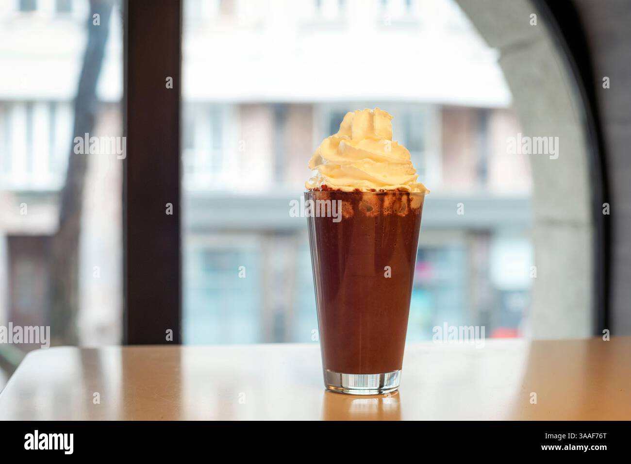 Bicchiere di cioccolata calda con panna montata sul tavolo del caffè. Foto Stock