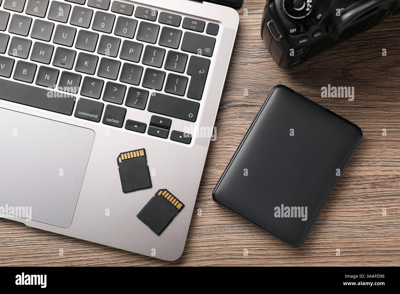 Unità disco rigido con cavo USB, lettori di schede, fotocamera e laptop su un tavolo in legno, piano Foto Stock