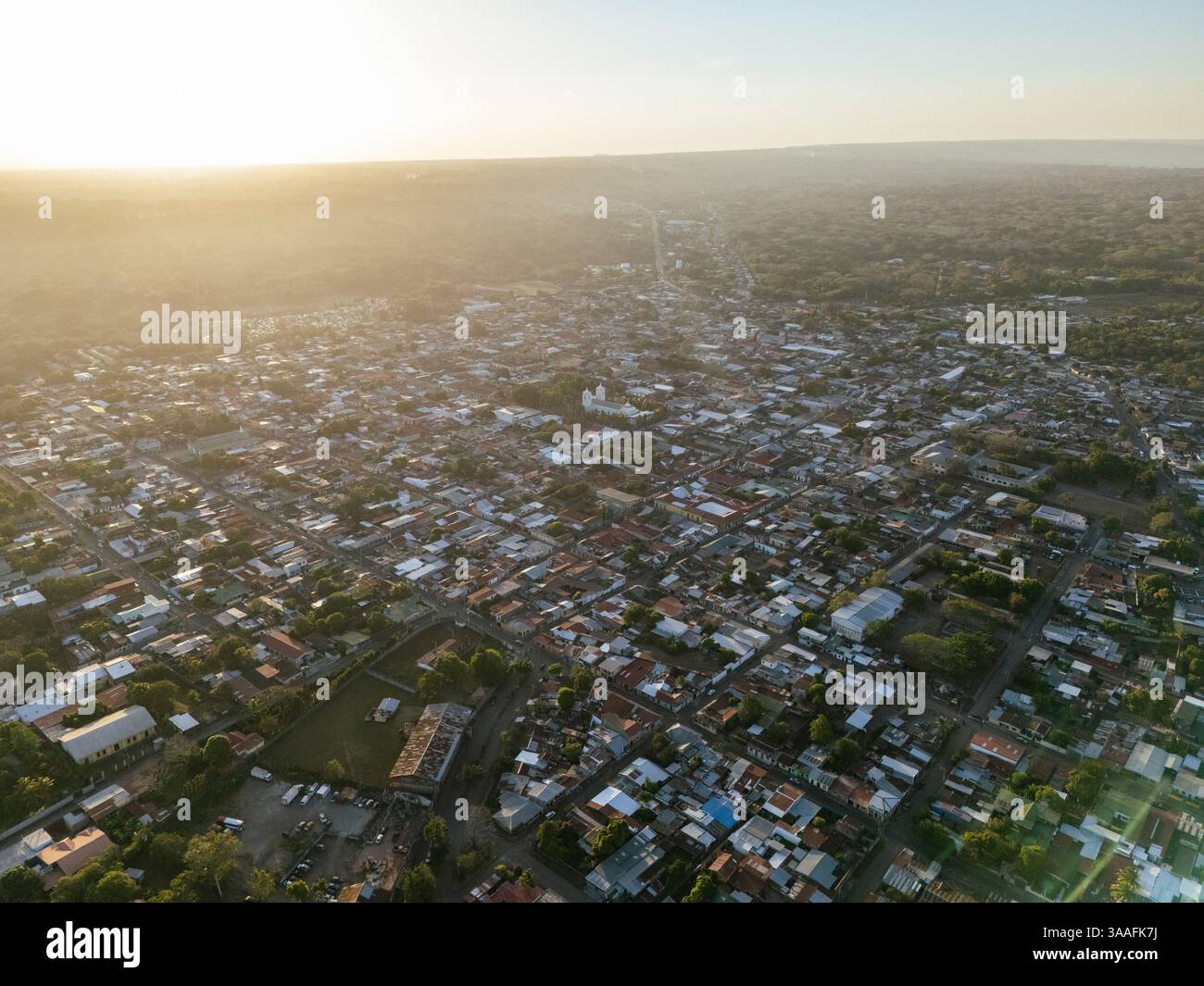Splendida prospettiva aerea della città di Jinotepe mentre il sole tramonta, illuminando tetti e strade sottostanti, creando un caldo bagliore. Foto Stock