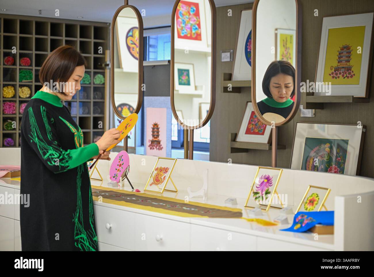 (250401) -- WUHAN, 1 aprile 2025 (Xinhua) -- Ren Wei organizza prodotti culturali e creativi nel suo studio a Wuhan, nella provincia di Hubei, nella Cina centrale, 14 marzo 2025. Il ricamo Han, un ricamo tradizionale con una storia di oltre 2.000 anni, è stato elencato come uno dei patrimoni culturali immateriali nazionali nel 2008. Famoso per le sue cuciture ruvide, i colori ricchi e i motivi audaci, spesso delinea i motivi del ricamo con linee oro o argento, offrendo un magnifico impatto visivo. Ren Wei, nato in una famiglia di ricami Han, è un erede rappresentativo dell'arte. Da quando aveva 14 anni Foto Stock