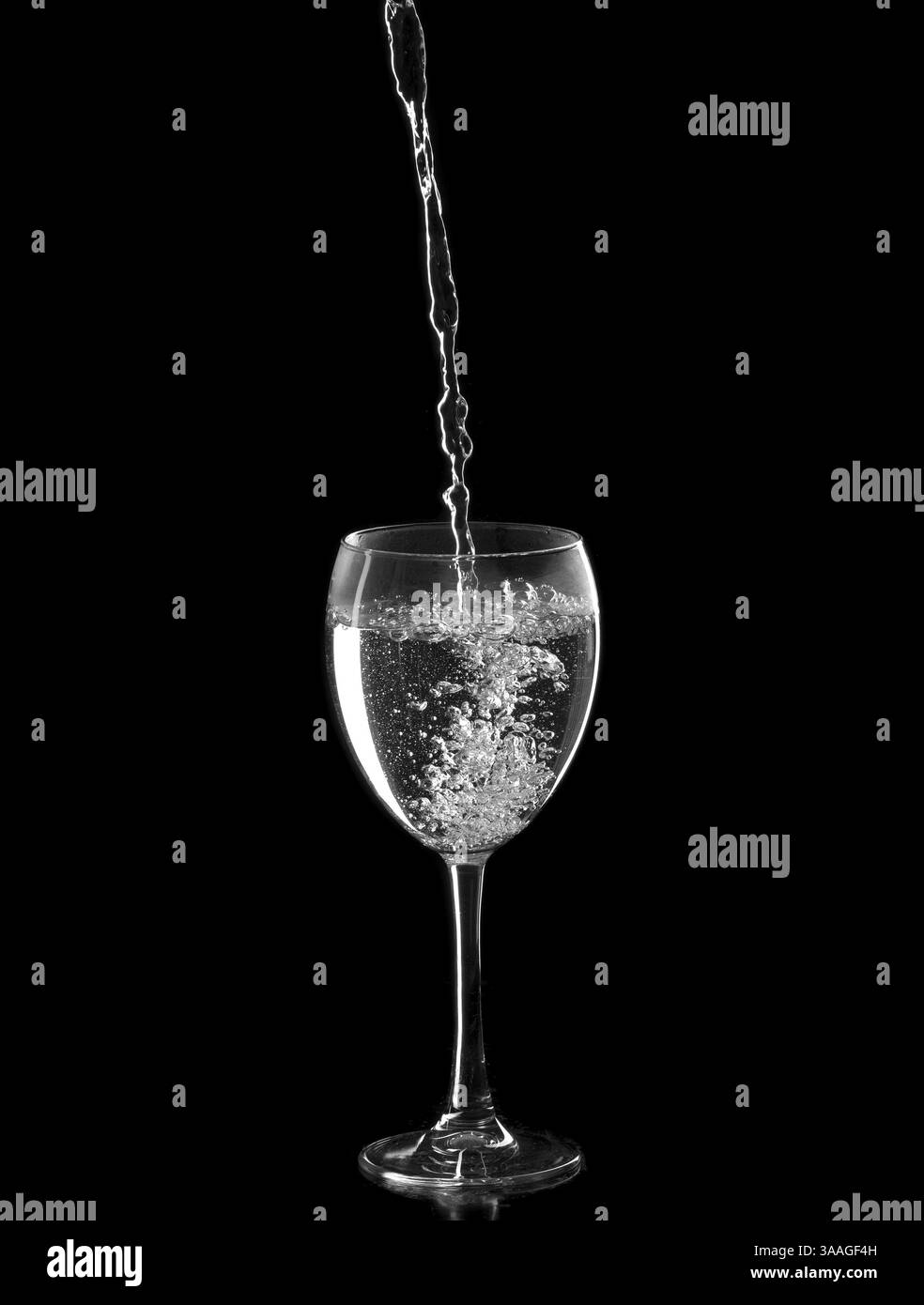 Acqua versata nel bicchiere di vino. Isolare sul nero Foto Stock