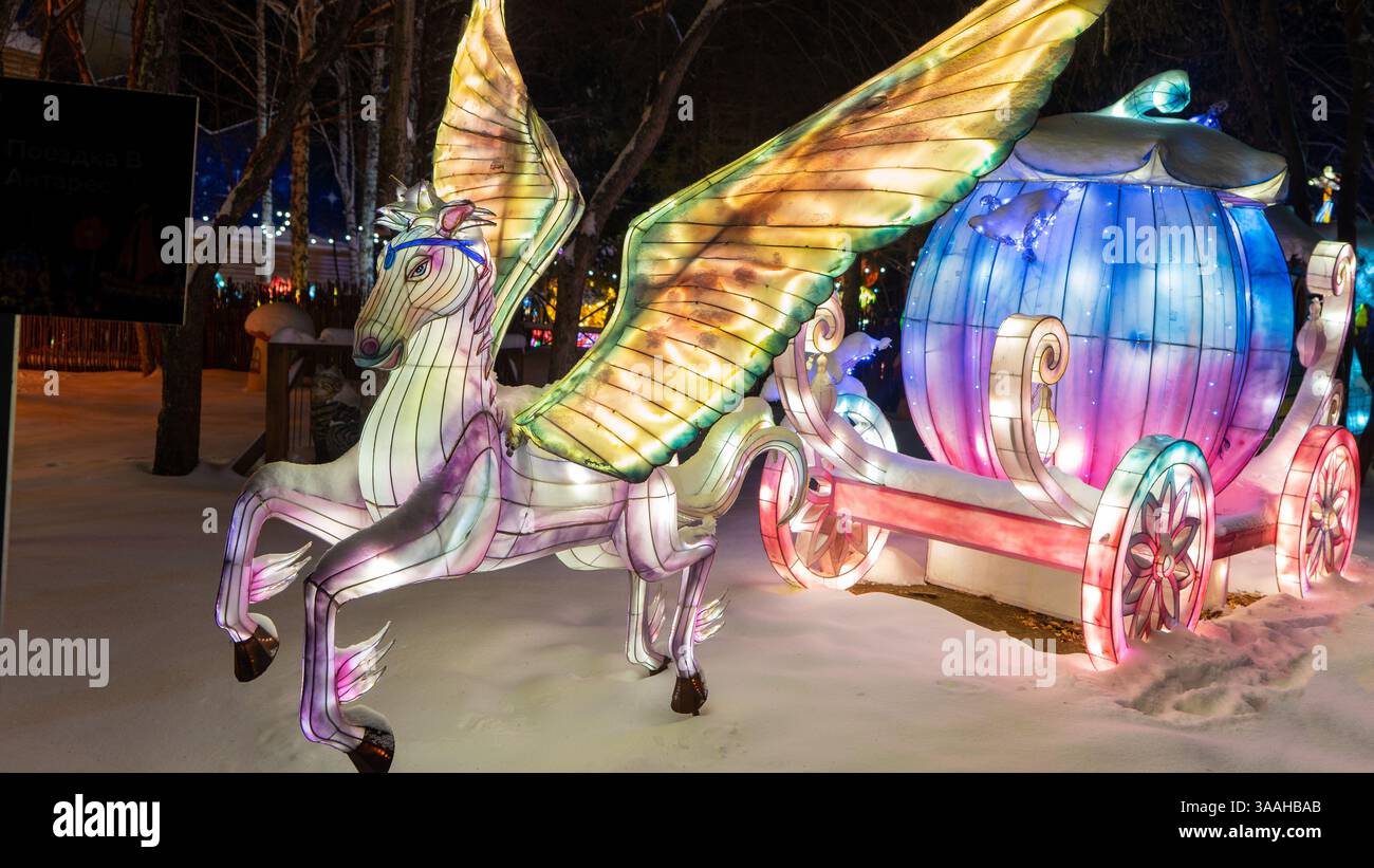 Decorazioni all'aperto in forma di luminosa carrozza Cenerentola sotto forma di zucca con pegaso in inverno in neve. Decorazioni invernali. Foto Stock