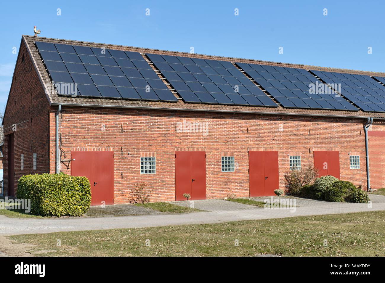 Un fienile in mattoni rossi con pannelli solari sul tetto nella bassa Sassonia rurale, Germania, che rappresenta un'agricoltura sostenibile e l'energia rinnovabile in agricoltura. Foto Stock