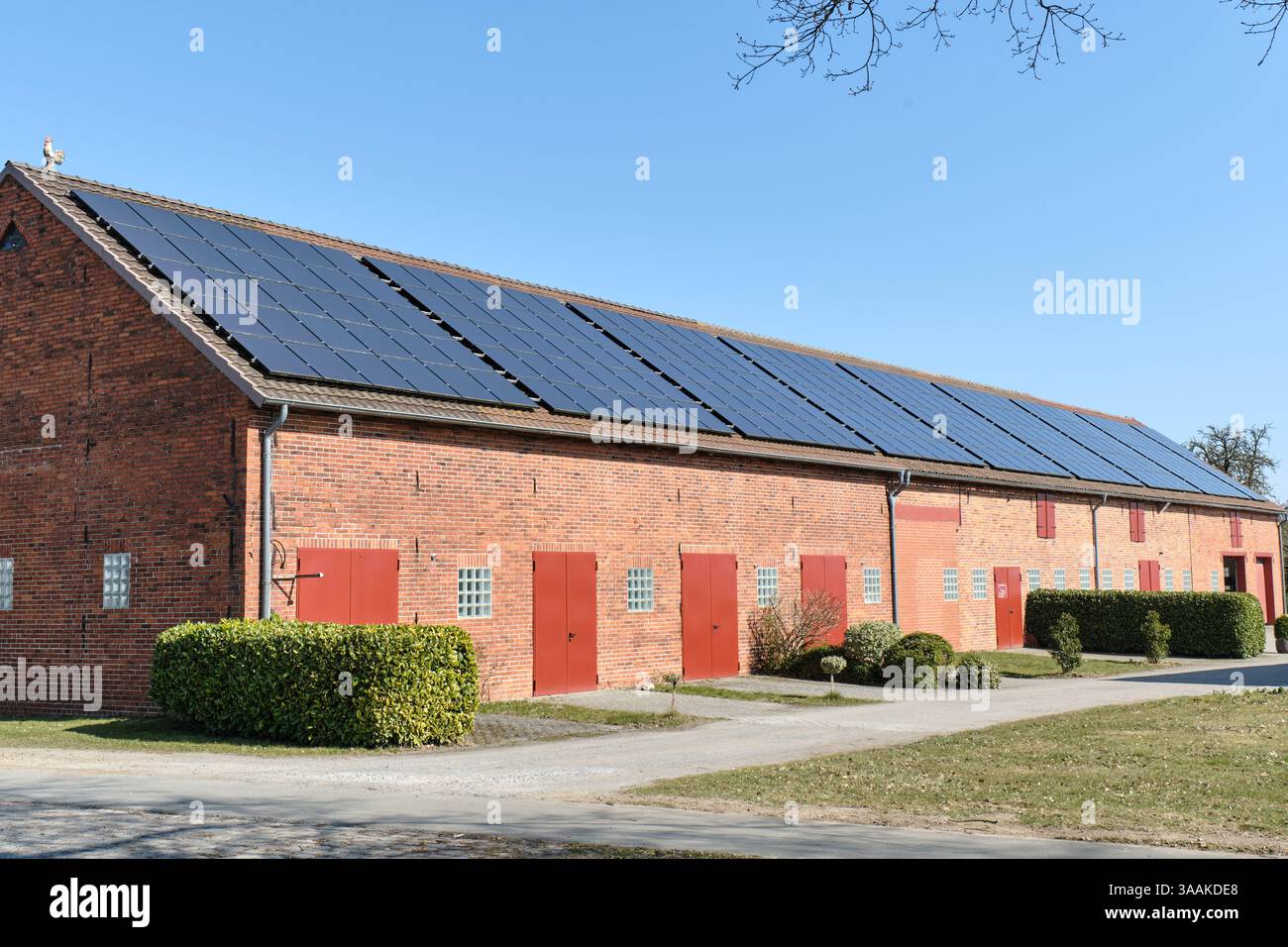 Un fienile in mattoni rossi con pannelli solari sul tetto nella bassa Sassonia rurale, Germania, che rappresenta un'agricoltura sostenibile e l'energia rinnovabile in agricoltura. Foto Stock