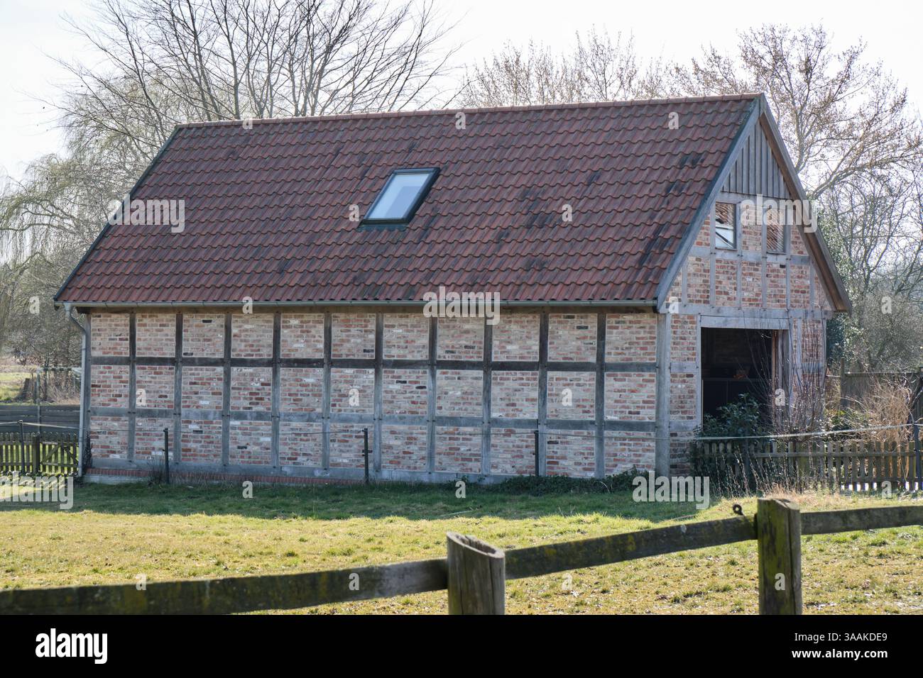 Un moderno fienile costruito in un tradizionale stile a metà legno con mattoni e legno nella bassa Sassonia rurale, Germania, che riflette l'artigianato storico e il des Foto Stock