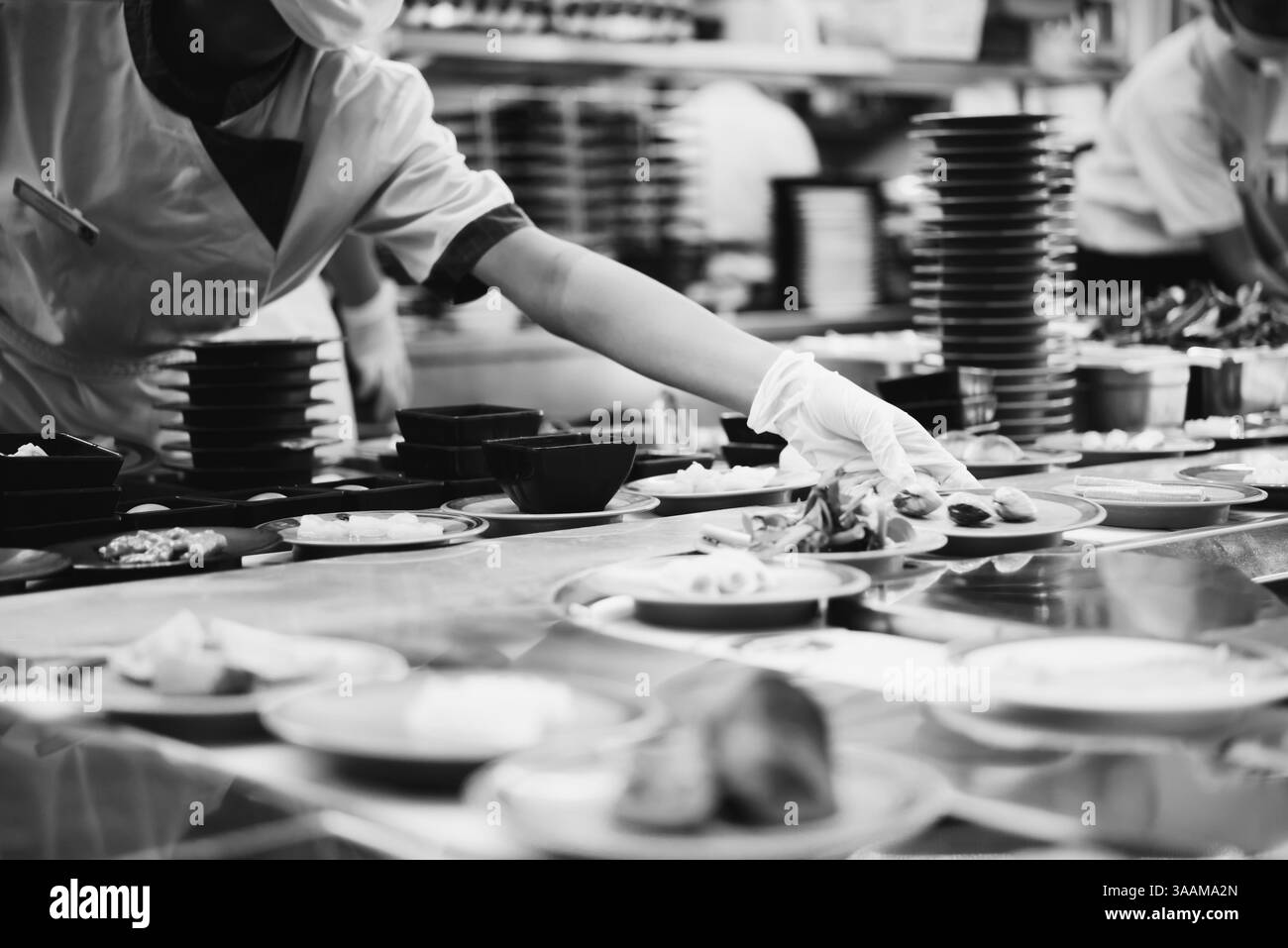 Chef che cucina un piatto nel ristorante giapponese, trasportatore di sushi o buffet a nastro per il servizio clienti in Thailandia Foto Stock