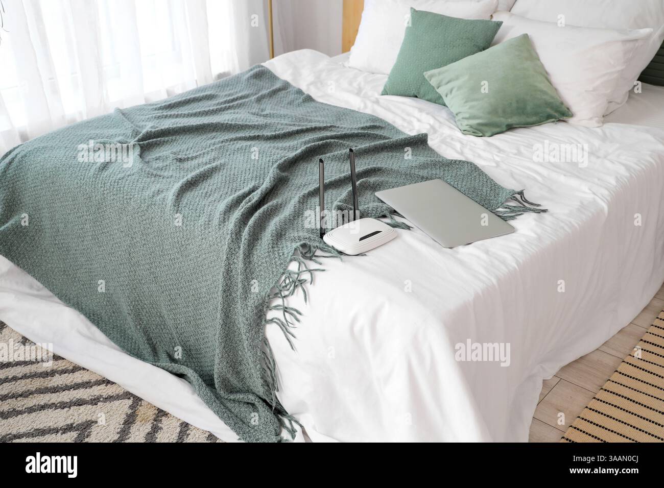 Moderno router wi-fi con laptop sul letto in camera Foto Stock