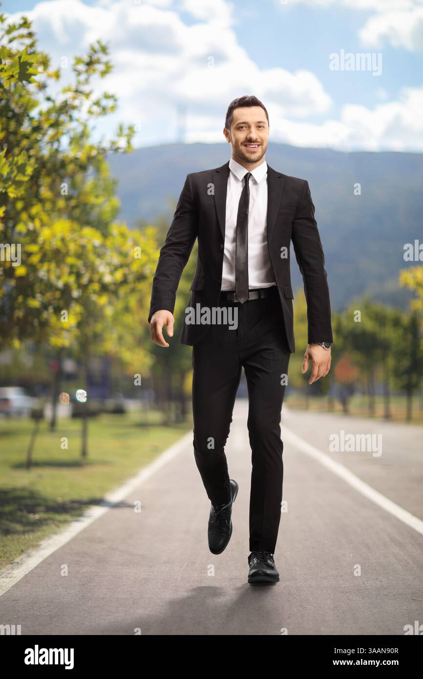 Ritratto completo di un uomo d'affari che cammina in un parco in una giornata di sole Foto Stock