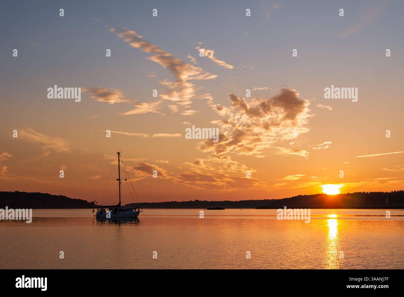 Barca a vela all'ancora nelle acque di bodden tra il porto di Barhöft e l'isola di Bock al tramonto nel Parco nazionale dell'area della laguna della Pomerania occidentale, Vorpommern-Rügen Foto Stock