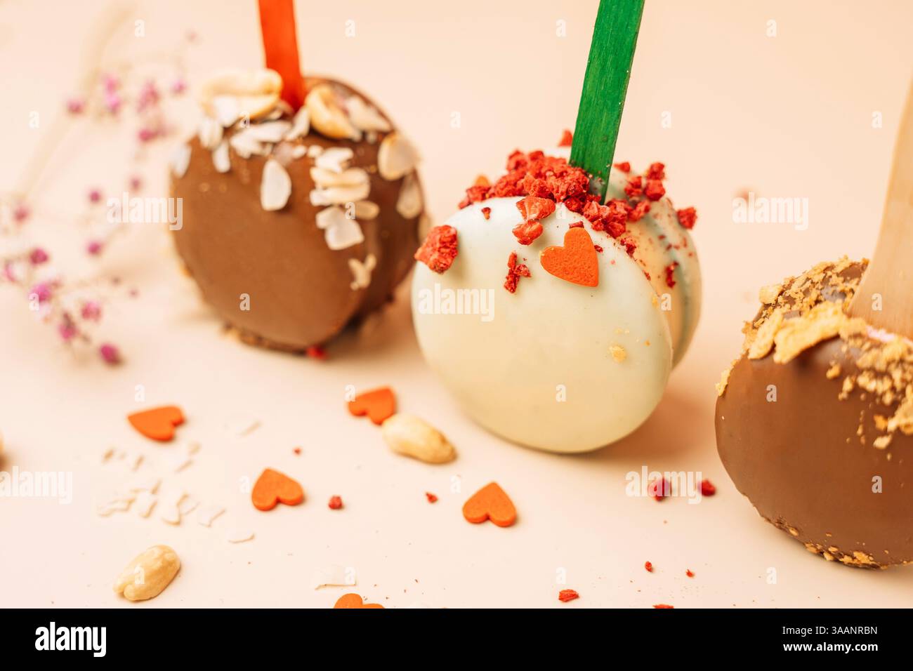 Dessert francesi al cioccolato. Macaron per torte su sfondo rosa, colori pastello, macaroon decorati con noci e cuori diversi, Foto Stock