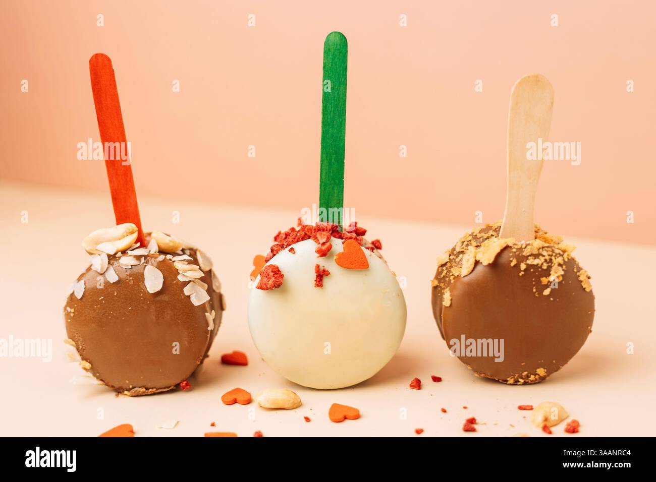 Dessert francesi al cioccolato. Macaron per torte su sfondo rosa, colori pastello, macaroon decorati con noci e cuori diversi, Foto Stock