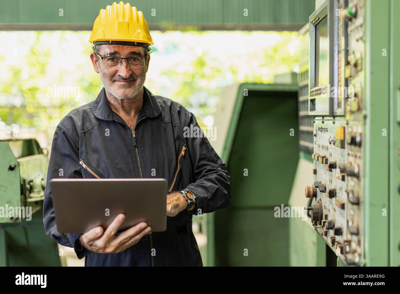 Ritratto Senior Professional tecnico ingegnere supervisore maschio con macchina industriale pesante CNC in fabbrica maniglia computer portatile. Foto Stock
