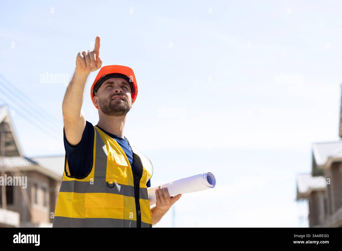 Uomo lavoratore caucasico con piano del pavimento in piedi con la mano rivolta verso l'alto per il responsabile del progetto del cantiere all'aperto, Foto Stock