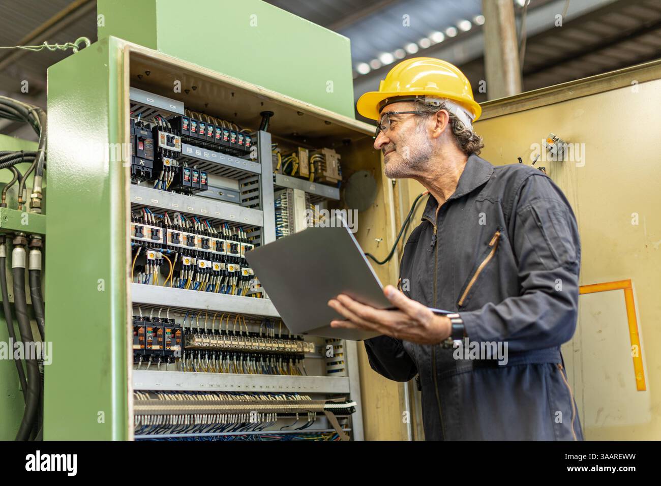 Senior Professional Electrician ingegnere supervisore servizio controllo manutenzione macchina industria pesante cavo elettrico con computer portatile. Foto Stock