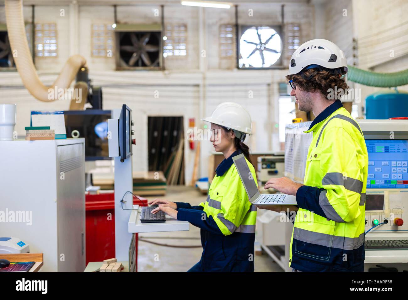 Tecnico professionista ingegnere giovane personale di lavoro di squadra i lavoratori controllano insieme la macchina CNC per legno Foto Stock