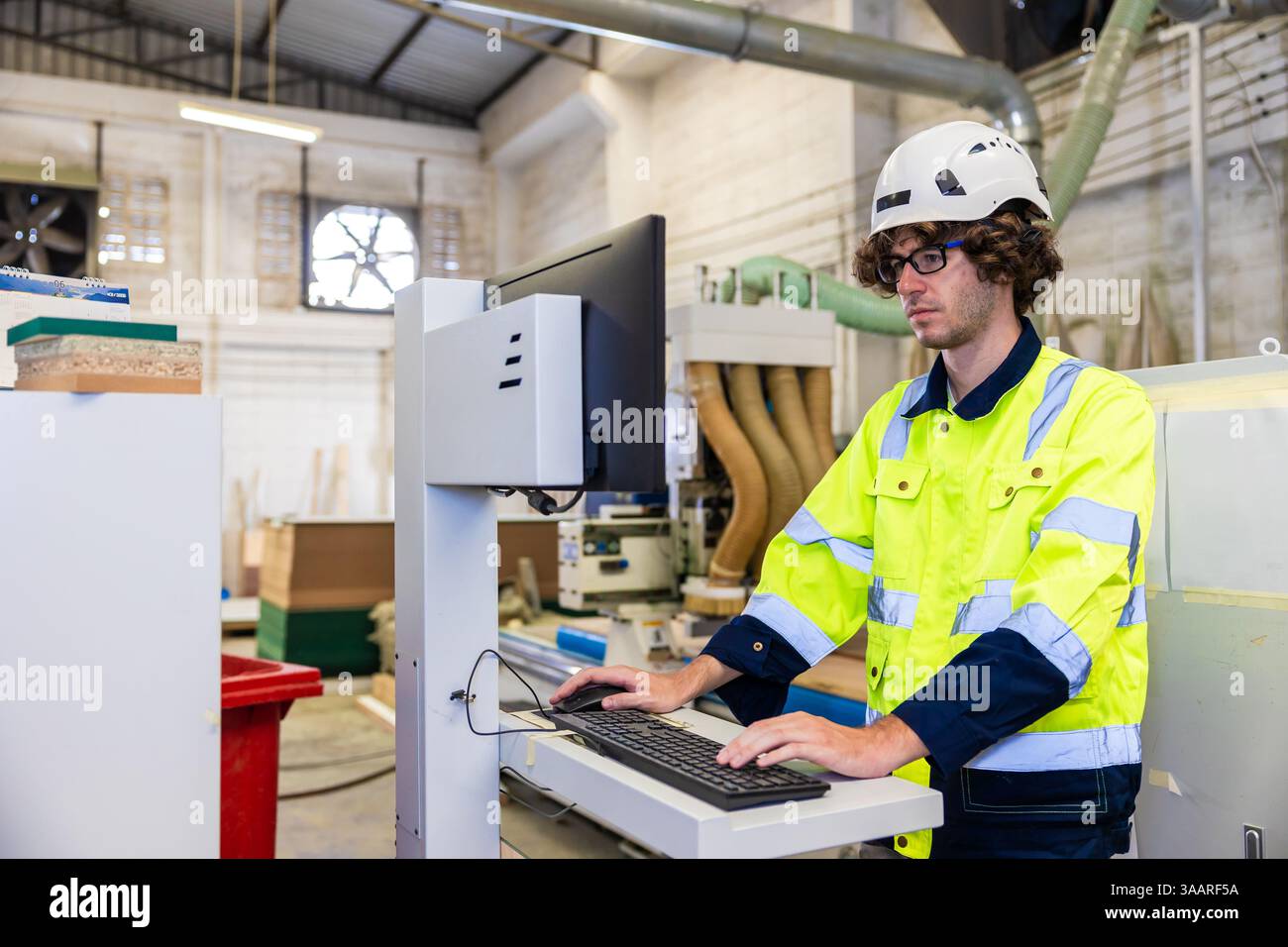 Tecnico professionista ingegnere giovane uomo Caucasico controllo lavoratore personale azionare macchina CNC legno Foto Stock