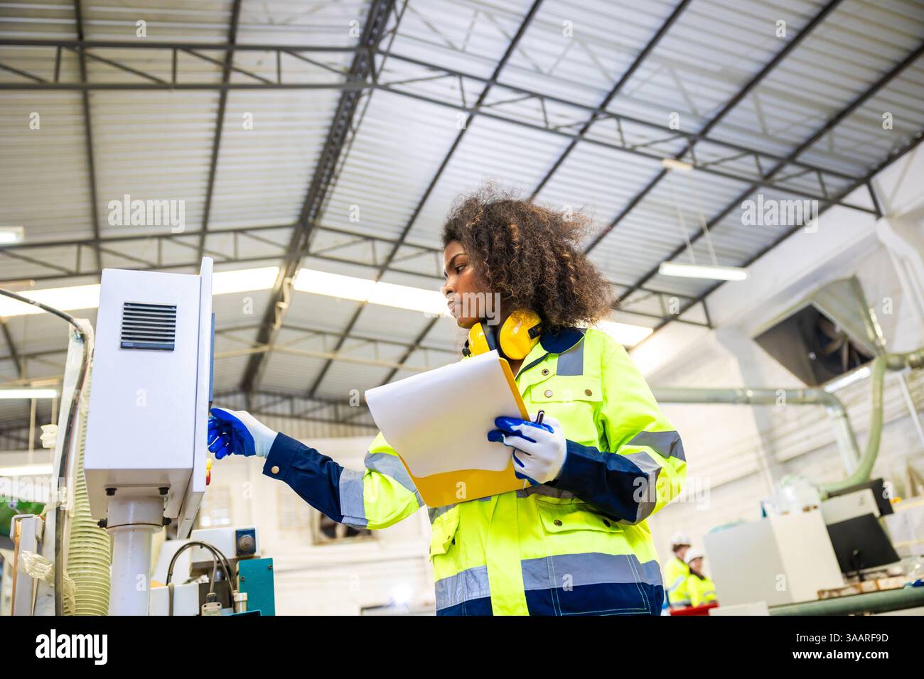 Le lavoratrici nere africane lavorano con l'industria della fabbrica di mobili della taglierina del legno con tuta di sicurezza Foto Stock