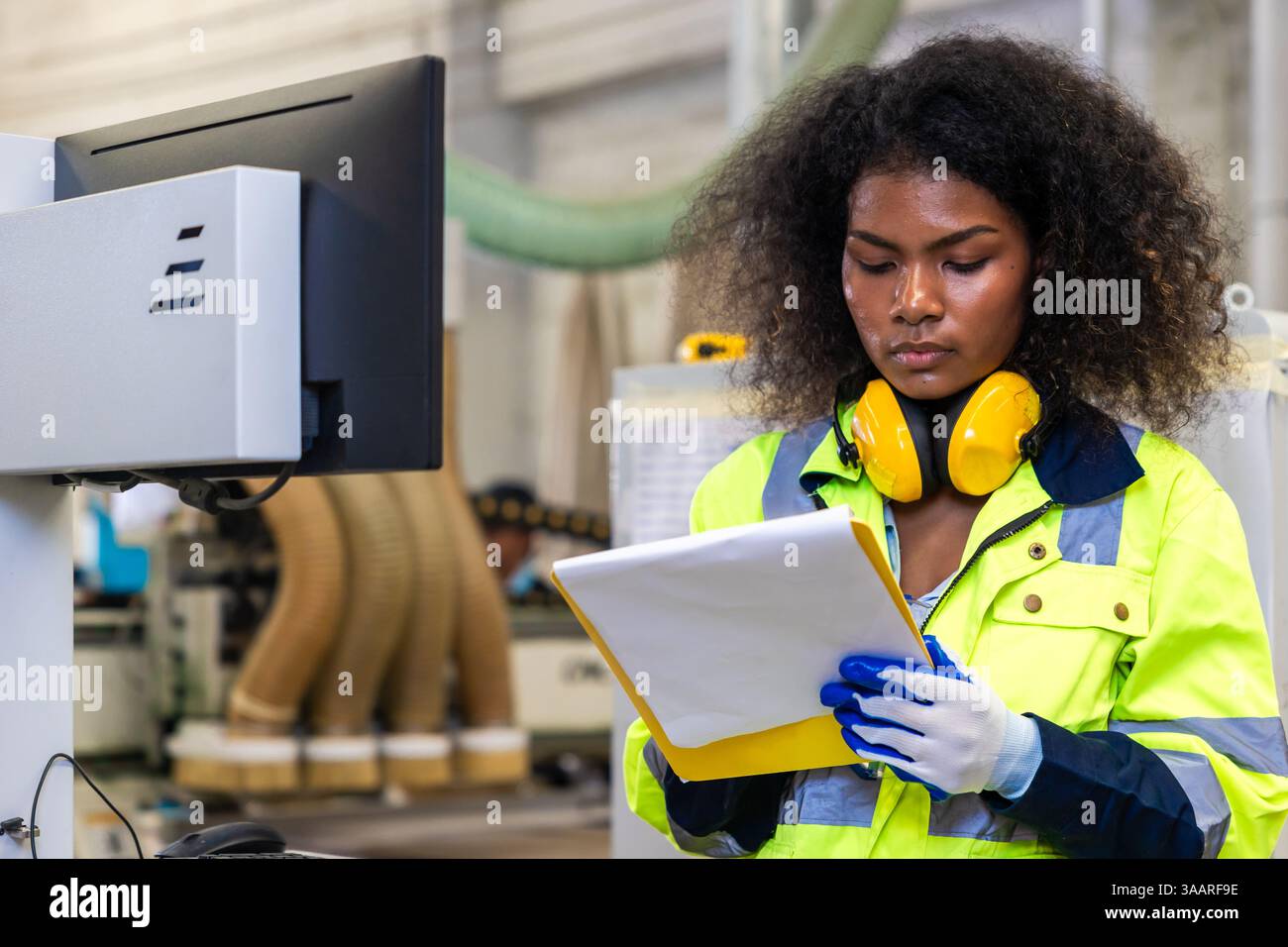 Le lavoratrici nere africane lavorano con l'industria della fabbrica di mobili della taglierina del legno con tuta di sicurezza Foto Stock