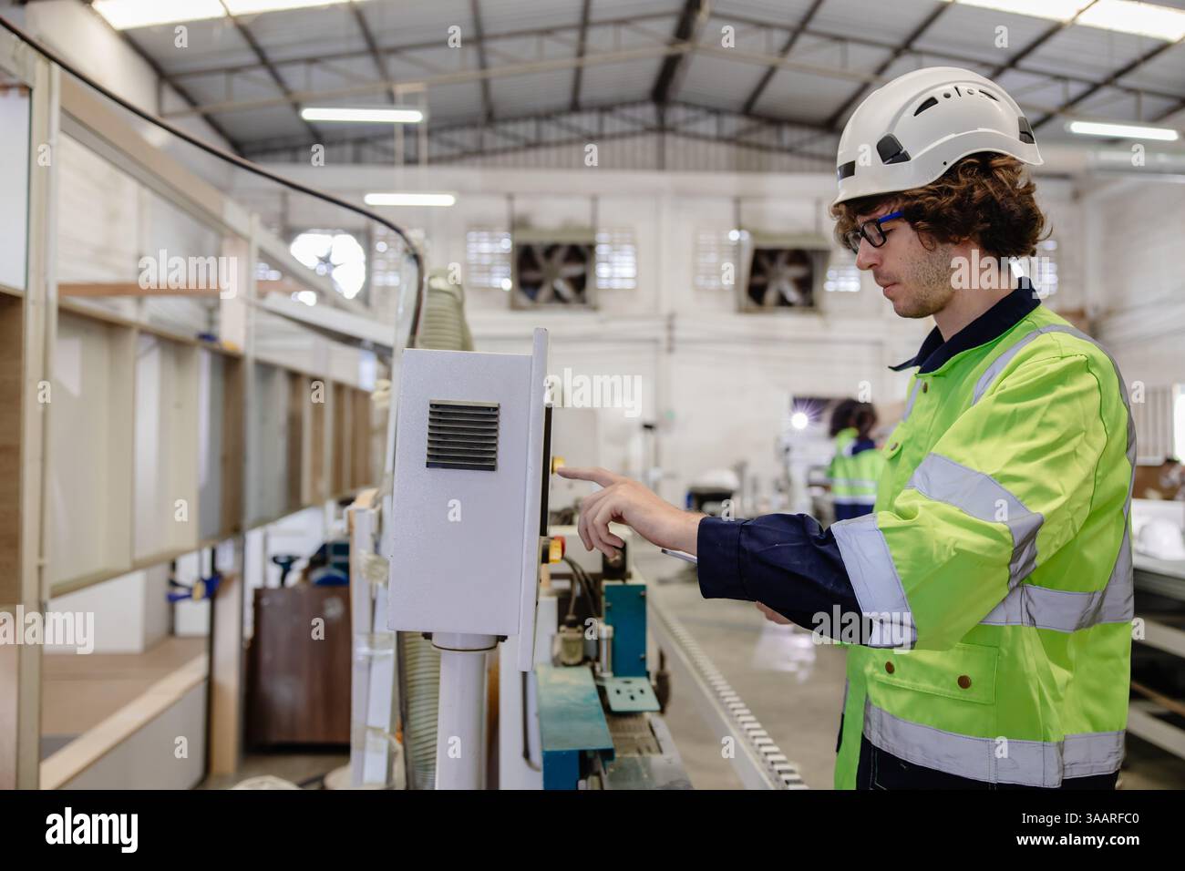 Giovane tecnico professionista tecnico tecnico tecnico tecnico personale maschile controllo operante macchina CNC per legno Foto Stock