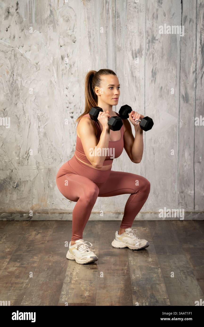Donna incinta che fa esercizio con manubri, promuovendo fitness e benessere durante la gravidanza Foto Stock