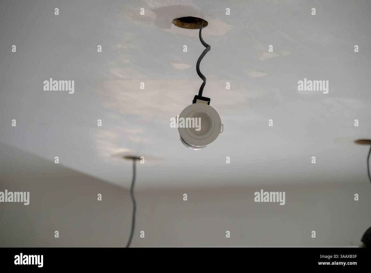 Cavi a soffitto e faretti esposti durante la ristrutturazione, catturando la fase grezza dell'installazione elettrica e degli aggiornamenti degli interni moderni Foto Stock