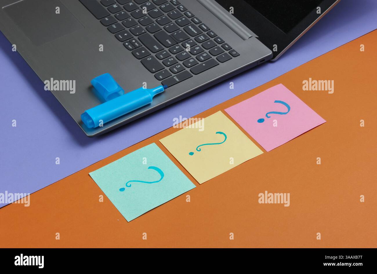 Laptop, fogli di carta con punti interrogativi disegnati e pennarello su sfondo marrone viola. Vista dall'alto Foto Stock