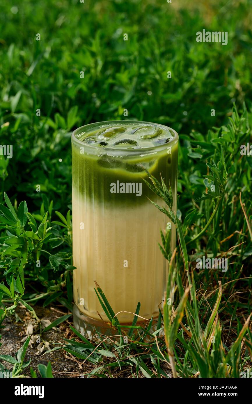 Latte matcha con tè verde freddo in un bicchiere con sfondo verde Foto Stock