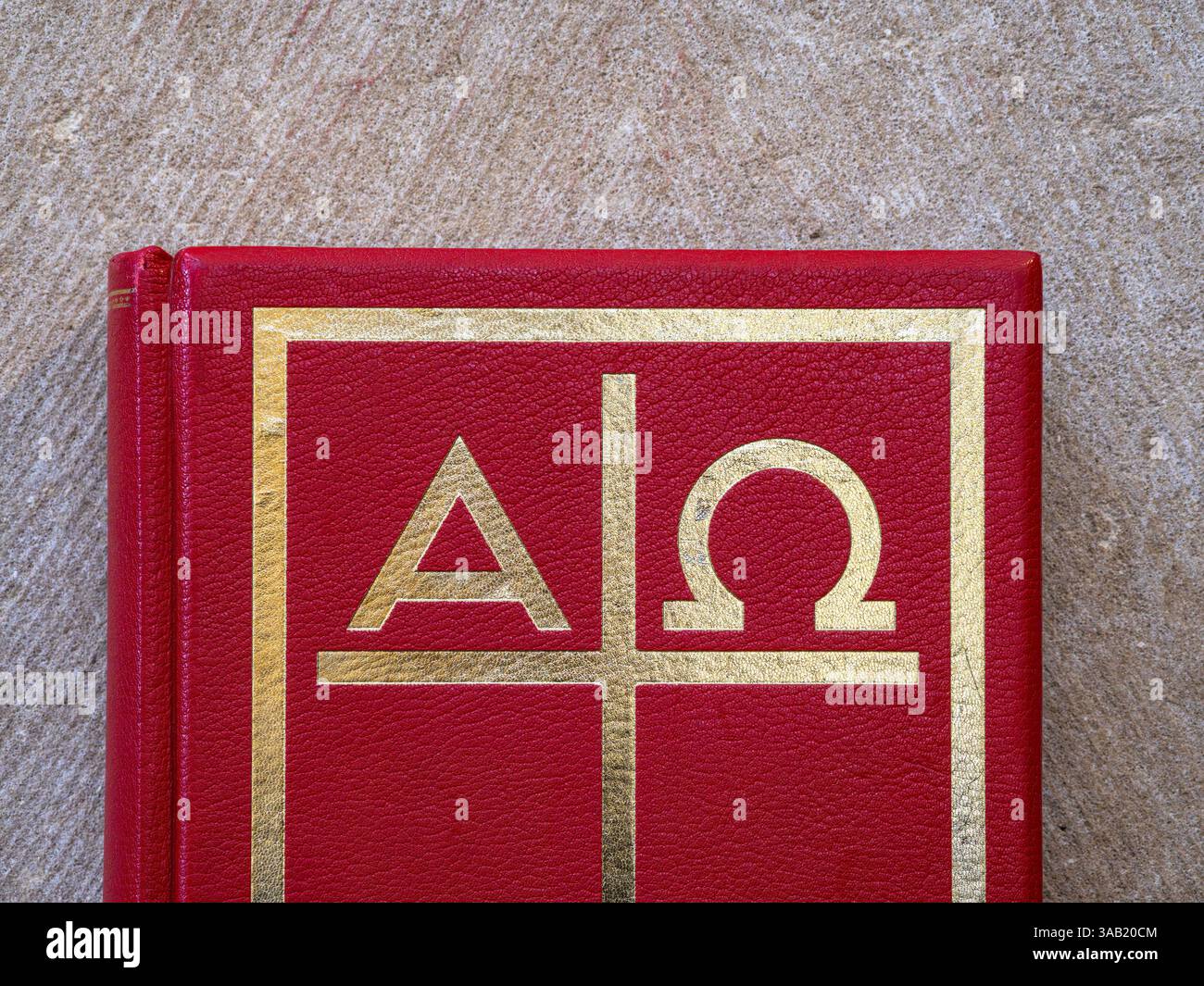 Altotting, Germania - 19 marzo 2025: Una vista ravvicinata di una copertina rossa di un libro religioso con simboli in rilievo d'oro, tra cui le lettere greche Alpha Foto Stock