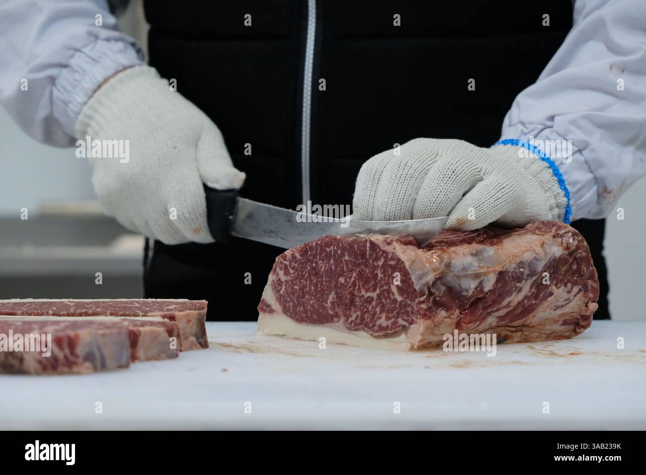 I dipendenti dell'azienda di produzione tagliano la carcassa di manzo e la tagliano a pezzi Foto Stock