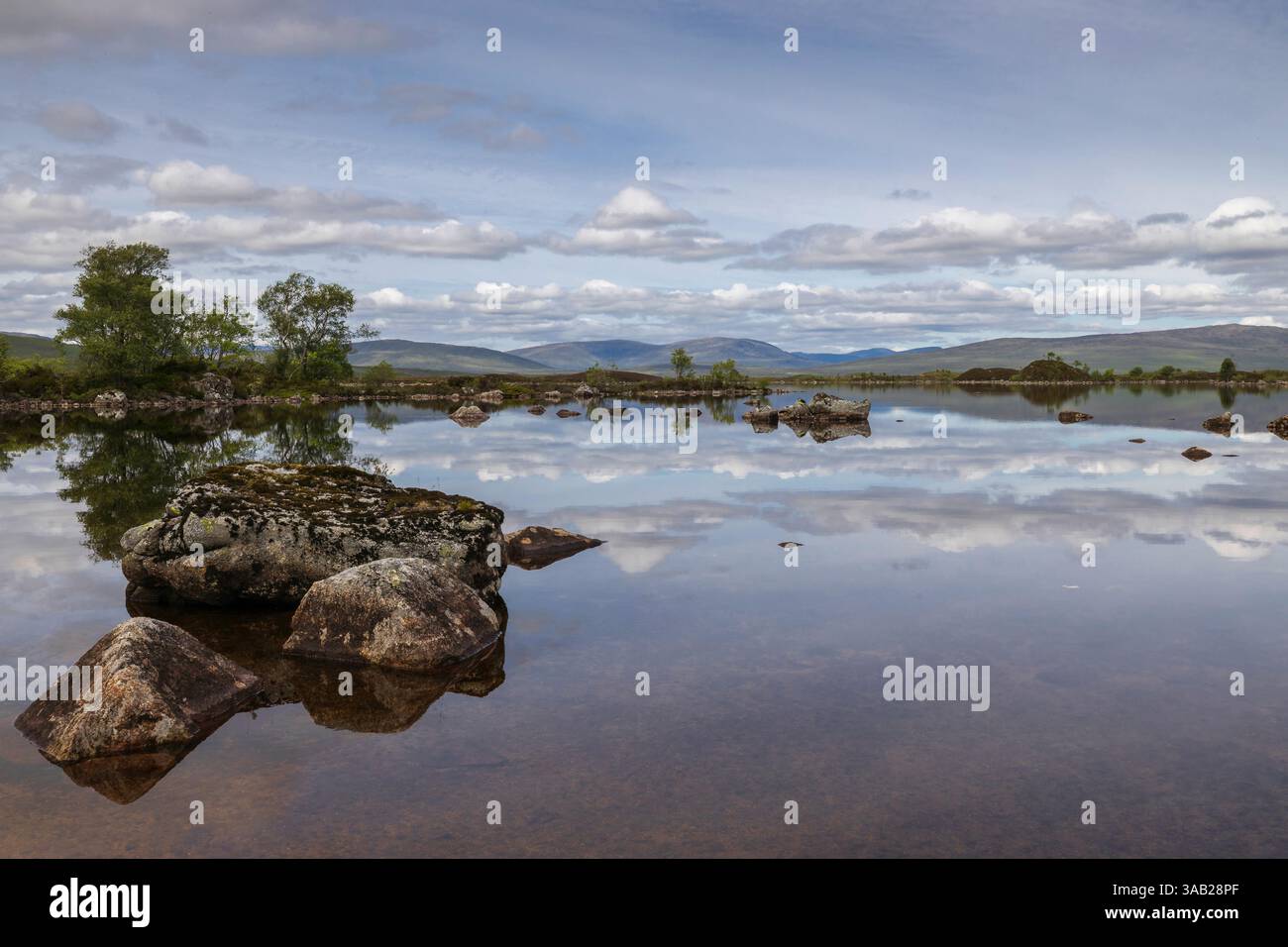 nuvole sussurrate nelle pianure scozzesi vicino a un lago con rocce Foto Stock
