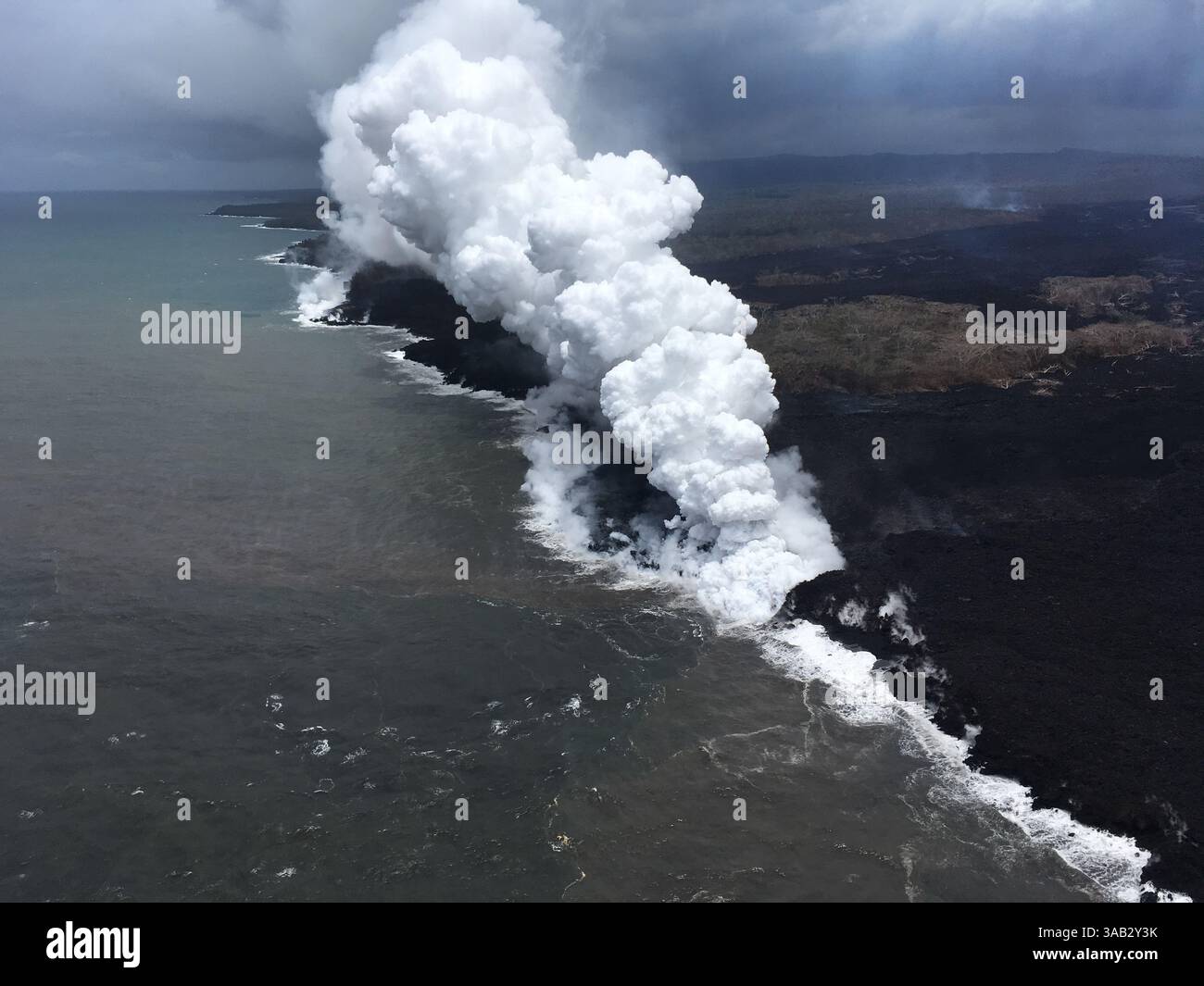 26 maggio 2018 - Pahoa, HI, Stati Uniti d'America - i pennacchi di Lava e di anidride solforosa velenosa sorgono quando il magma fuso raggiunge l'oceano dall'eruzione del vulcano Kilauea 26 maggio 2018 a Pahoa, Hawaii. La lava calda che entra nell'oceano crea un denso pennacchio bianco chiamato ''Laze'' (abbreviazione di ''lava haze''). Il lazo si forma quando la lava calda fa bollire l'acqua di mare fino alla secchezza. Il processo porta a una serie di reazioni chimiche che creano una nube bianca fluttuante composta da un vapore condensato di acqua di mare, gas acido cloridrico e piccoli frammenti di vetro vulcanico. La nuvola è corrosiva quanto l'acido diluito della batteria e la cenere Foto Stock
