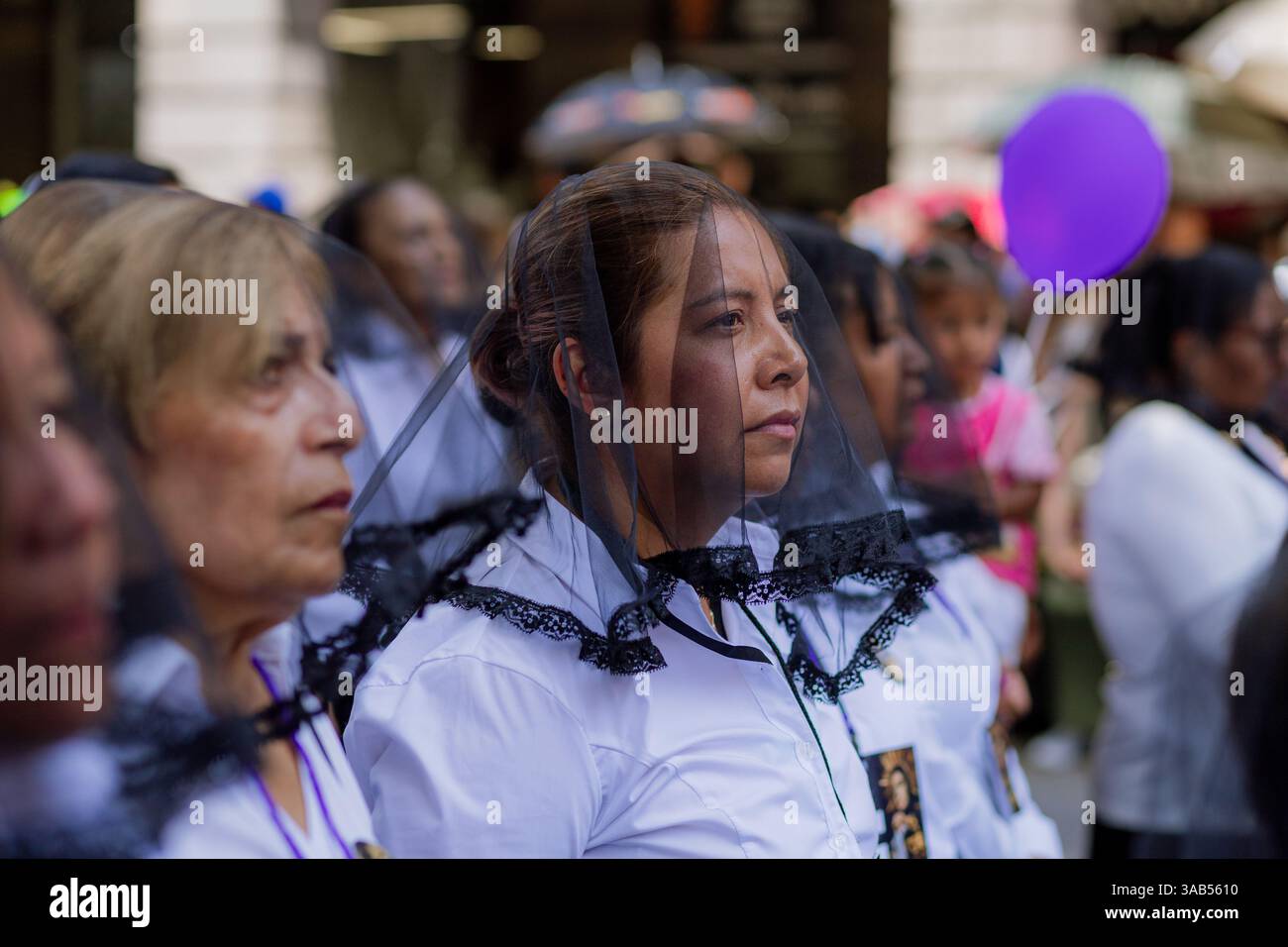 Le donne camminano con devozione nella processione del venerdì Santo a Puebla, vestite con abiti tradizionali in un'atmosfera di profonda spiritualità e riverenza Foto Stock