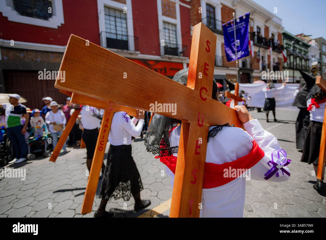 Le donne camminano con devozione nella processione del venerdì Santo a Puebla, vestite con abiti tradizionali in un'atmosfera di profonda spiritualità e riverenza Foto Stock