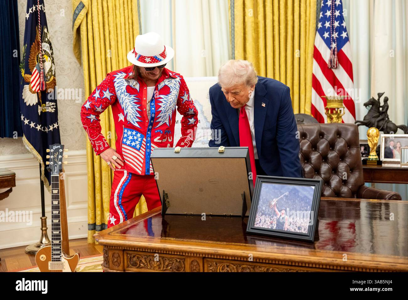 Washington, Stati Uniti. 31 marzo 2025. Musicista Kid Rock, Left e U. Presidente Donald Trump, guarda un revolver placcato oro donato da Kid Rock durante la firma di un ordine esecutivo che proibisce lo scalping del biglietto sfruttativo presso l'Ufficio ovale della Casa Bianca, 31 marzo 2025 a Washington, DC Credit: Molly Riley/White House Photo/Alamy Live News Foto Stock