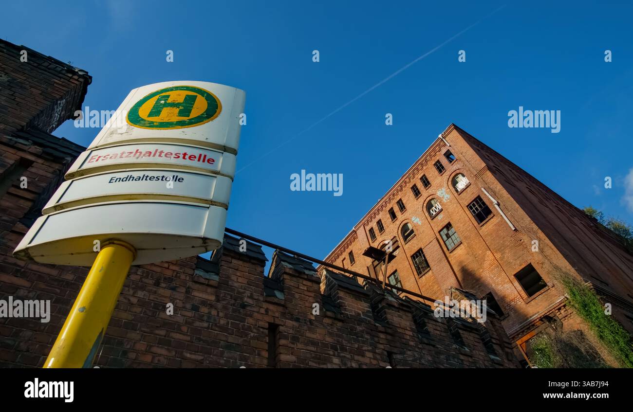 Il cartello della fermata dell'autobus "Ersatzhaltestelle" si trova di fronte alla storica e abbandonata fabbrica di birra Bärenquell a Berlino, Germania, con vista grandangolare. Foto Stock