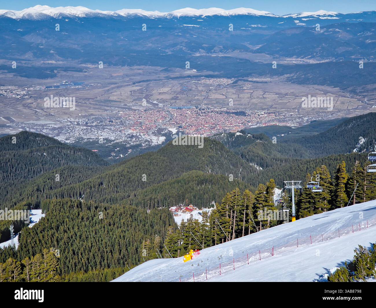 Località sciistica di Bansko sui monti Pirin con seggiovie che si spostano sopra le piste innevate e una splendida vista che scende dalla collina fino al centro storico - Immagine stock catturata con smartphone